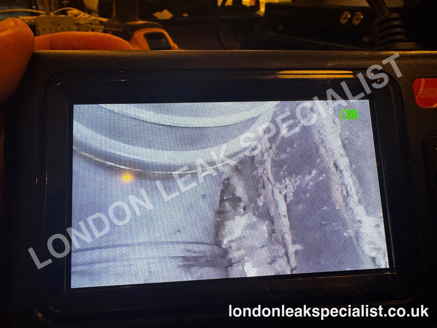 The screen of an inspection camera showing the inside of a ceiling void with pipework